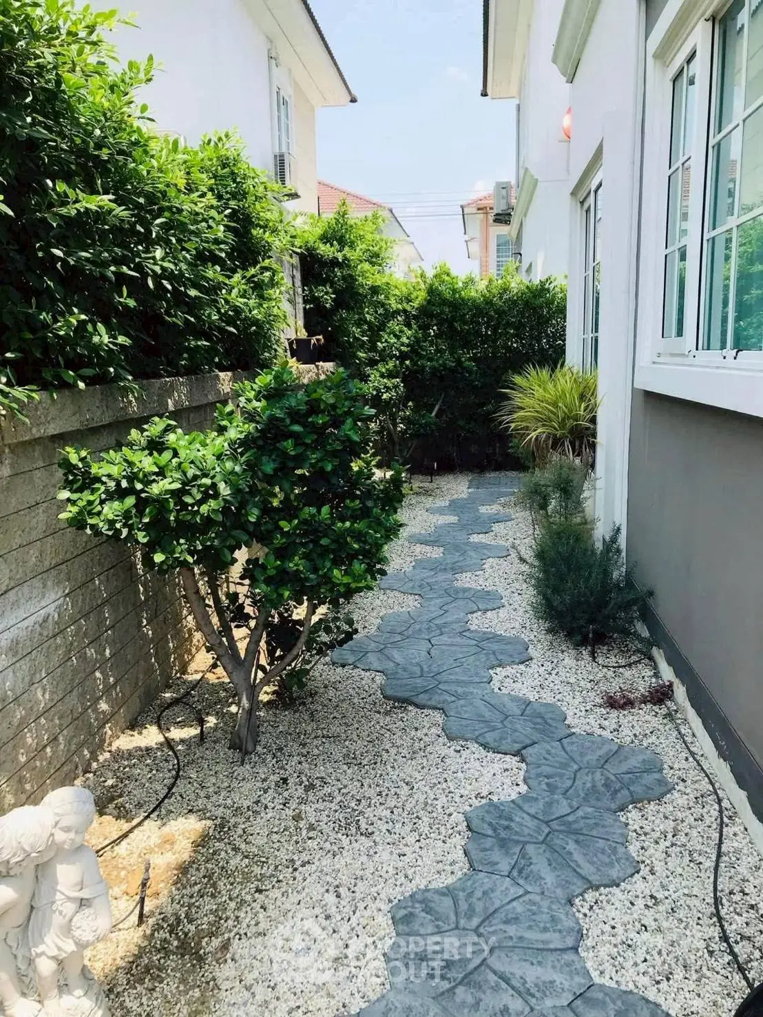Charming garden pathway with lush greenery and decorative stone walkway, perfect for serene outdoor living.