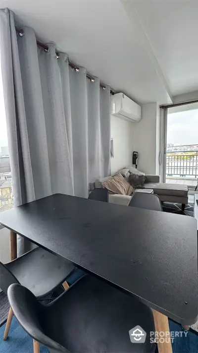 Modern living room with sleek black dining table and city view balcony