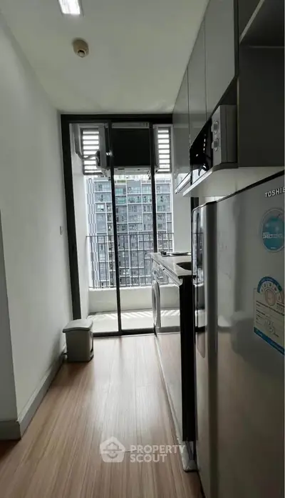 Modern kitchen with sleek appliances and city view from balcony.