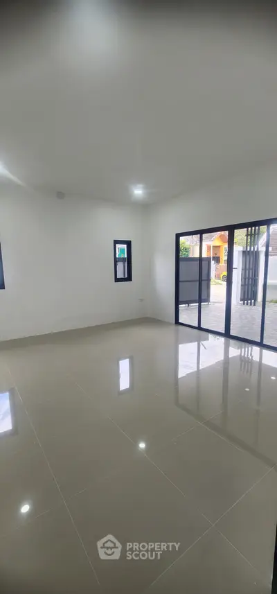 Spacious empty room with large windows and glossy tiled floor