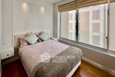 Cozy bedroom with large window offering natural light and modern decor in urban apartment.