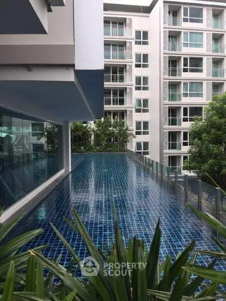 Modern apartment building with a stunning rooftop pool and lush greenery.