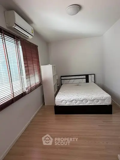 Cozy bedroom with natural light, featuring a comfortable bed and sleek wooden flooring.