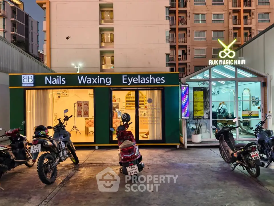 Modern commercial building with beauty salon and nail spa, vibrant signage, and motorbike parking in urban setting.