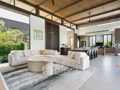 Luxurious open-plan living room with modern decor and garden view, featuring high ceilings and elegant furnishings.