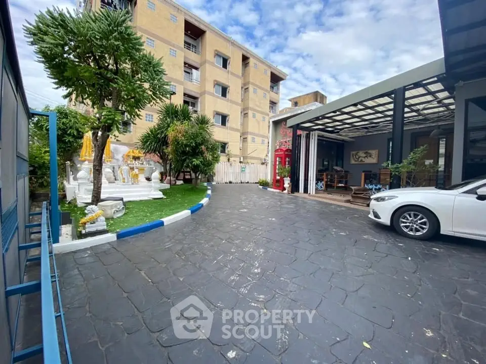 Charming exterior with lush garden and spacious parking area in modern residential complex.