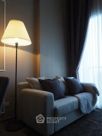 Cozy living room with elegant sofa and floor lamp near large window