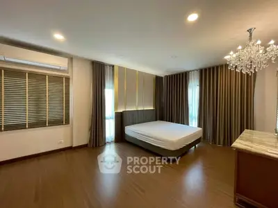 Spacious bedroom with elegant chandelier and large windows in modern apartment