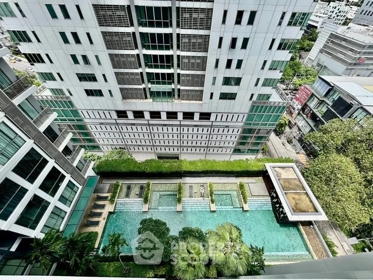 Stunning aerial view of modern building with luxurious pool and lush greenery.