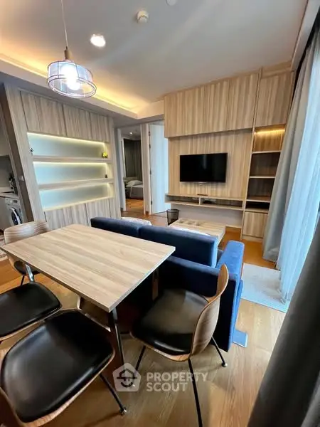 Modern living room with stylish furniture and open layout, featuring a cozy dining area and sleek wooden finishes.