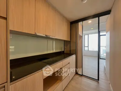 Modern kitchen with sleek wooden cabinetry and glass backsplash in a bright apartment