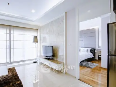 Modern open-plan living room with sleek TV unit and view into cozy bedroom.