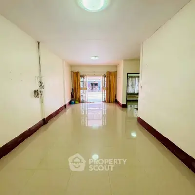 Spacious empty living room with large windows and tiled flooring, ready for customization.