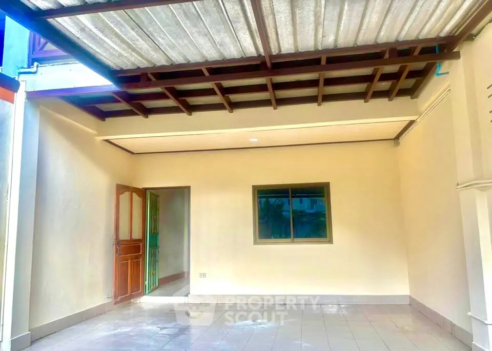 Spacious covered outdoor area with tiled flooring and window view, perfect for versatile use.