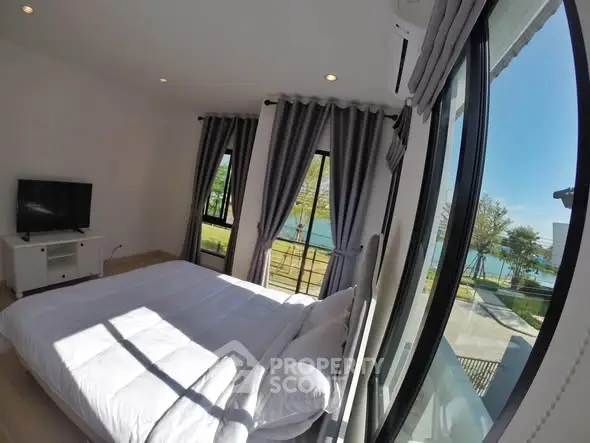 Bright bedroom with large windows offering stunning lake view, modern decor, and natural light.