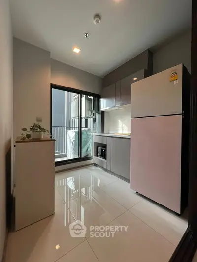 Modern kitchen with sleek cabinetry and large fridge in a compact layout.