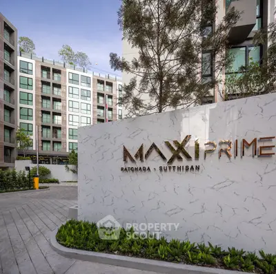 Modern apartment building with elegant entrance and lush greenery at Maxi Prime Ratchada Sutthisan.