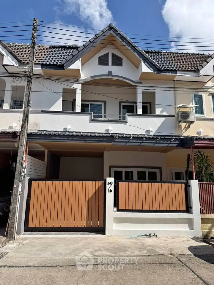 Charming two-story townhouse with modern facade and gated entrance in a serene neighborhood.