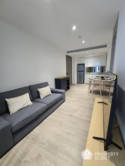 Modern living room with sleek furniture and open kitchen layout in a contemporary apartment.