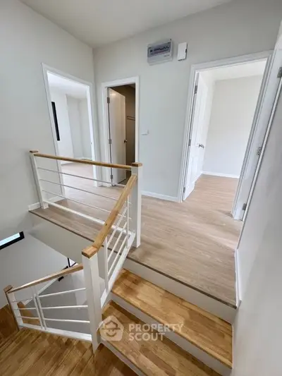 Modern staircase with wooden flooring and white railings in a bright home interior.