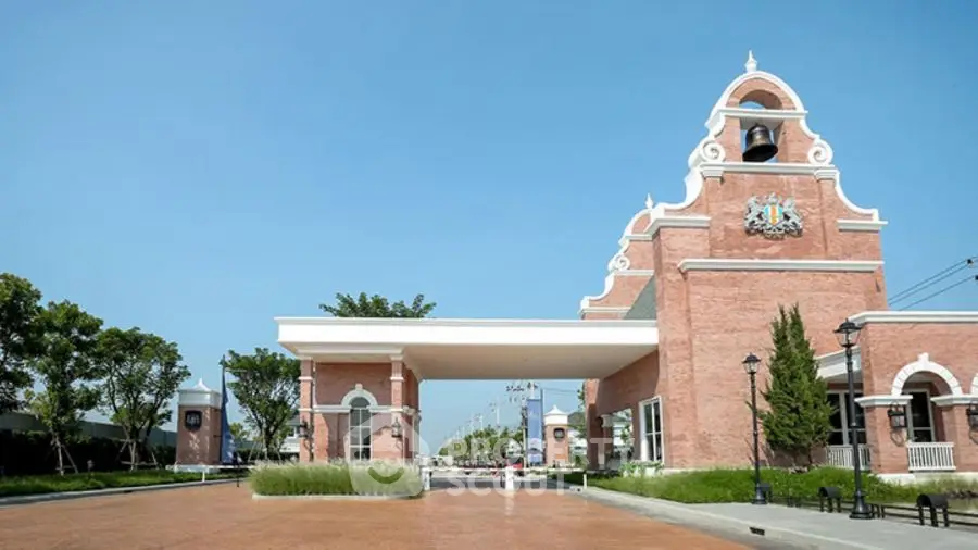 Elegant entrance of a luxury residential building with classic architecture and lush landscaping.