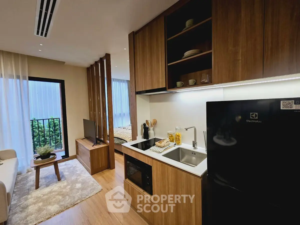 Modern open-plan living room and kitchen with sleek wooden finishes and natural light.