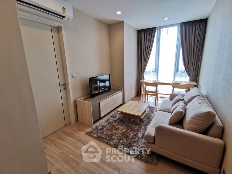 Modern living room with cozy sofa, TV, and natural light from large window.