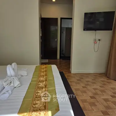 Cozy bedroom with modern decor and wall-mounted TV, perfect for relaxation.