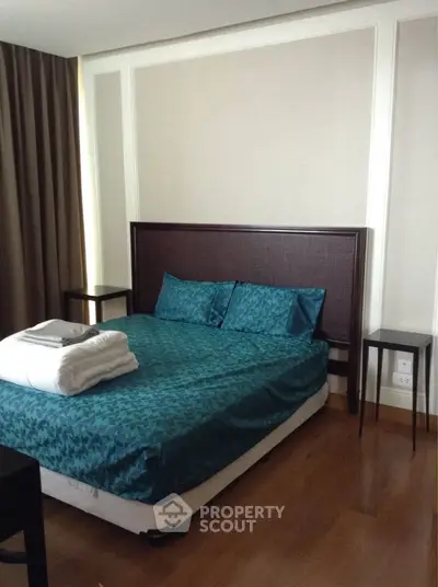 Cozy bedroom with elegant decor and wooden flooring, featuring a comfortable bed and stylish side tables.