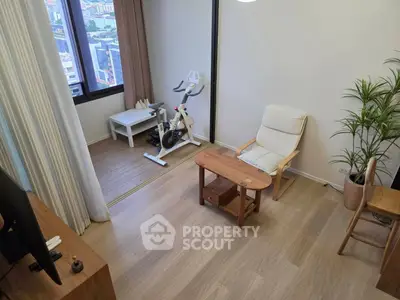 Modern living room with exercise bike and city view, featuring wooden flooring and cozy seating area.