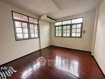Spacious room with hardwood floors and large windows in a well-lit interior space.