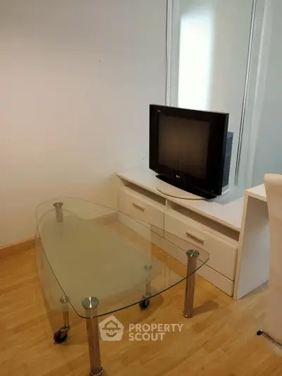 Modern living room with glass coffee table and TV on wooden floor