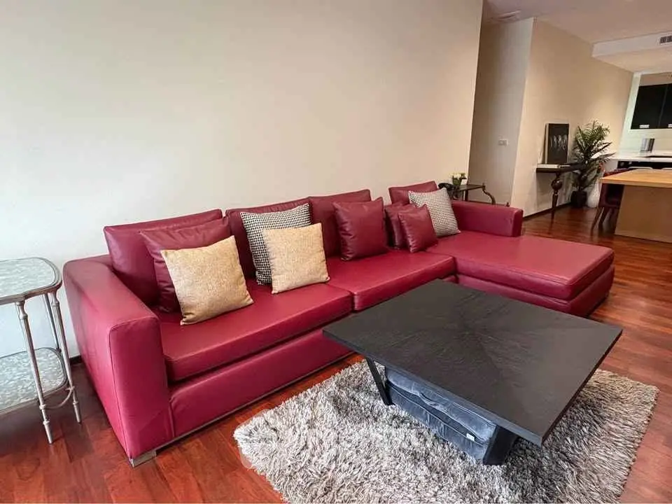 Stylish living room with red leather sofa and modern coffee table on wooden flooring.