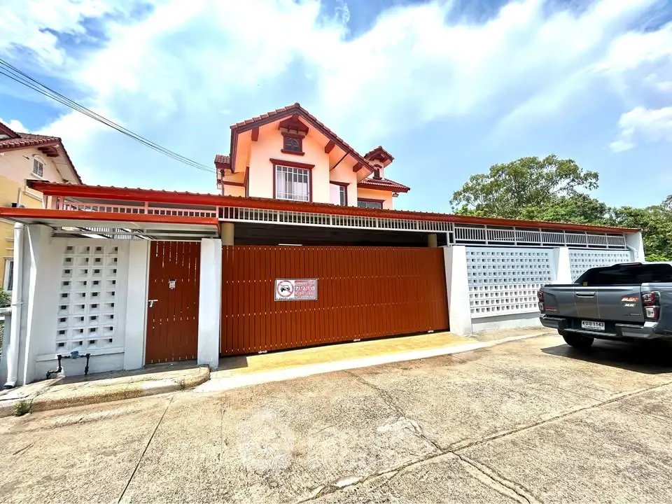 Charming two-story house with gated entrance and driveway in a sunny neighborhood.