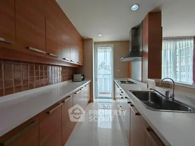 Spacious modern kitchen with sleek wooden cabinets and large windows for natural light.