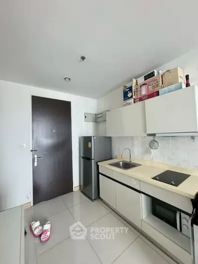 Modern compact kitchen with sleek cabinets and appliances in a stylish apartment.