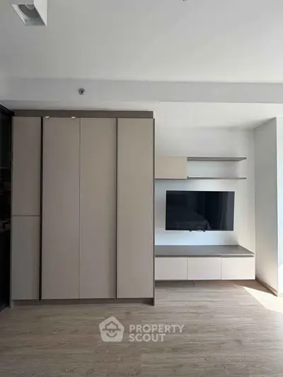 Modern living room with sleek built-in storage and mounted TV, featuring minimalist design and light wood flooring.