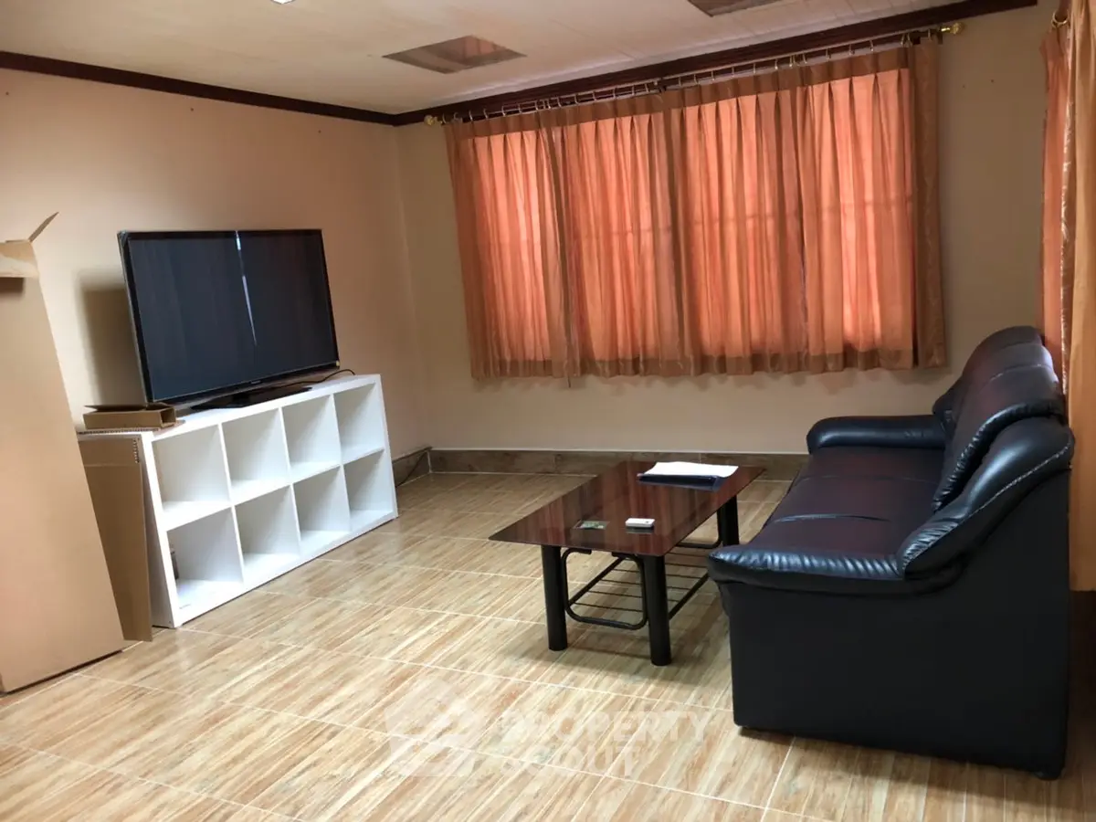 Cozy living room with leather sofa and large TV, perfect for relaxation.