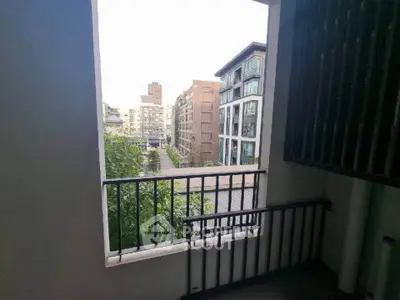 Modern urban apartment view with balcony overlooking cityscape and greenery.