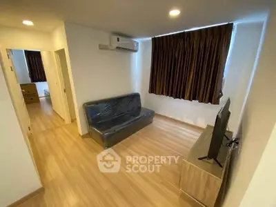 Modern living room with sleek design, featuring a compact sofa and wall-mounted TV, perfect for cozy living.