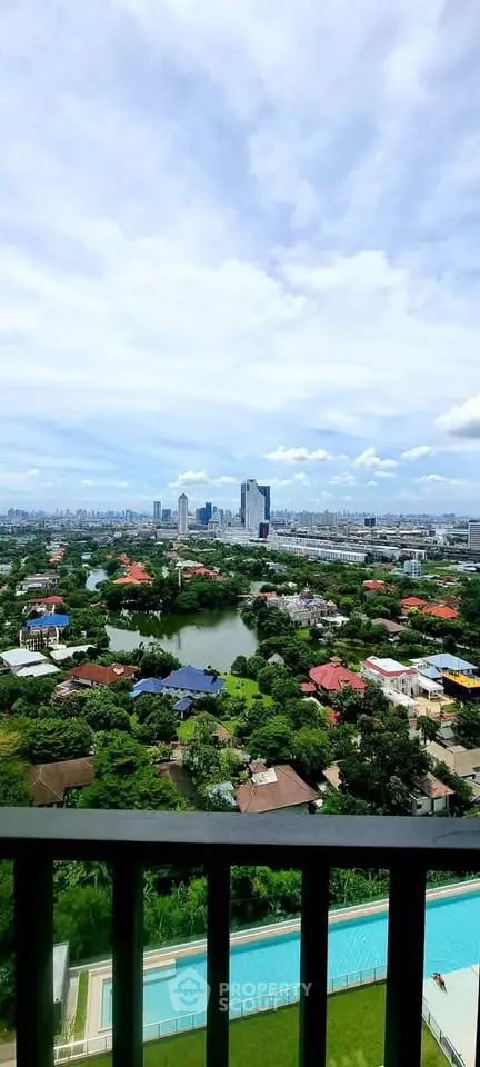 Stunning cityscape view from high-rise balcony overlooking lush greenery and skyline.