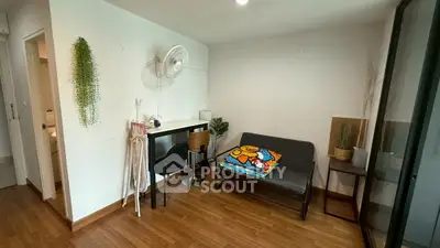 Cozy living room with modern decor and wooden flooring, featuring a small sofa and workspace.