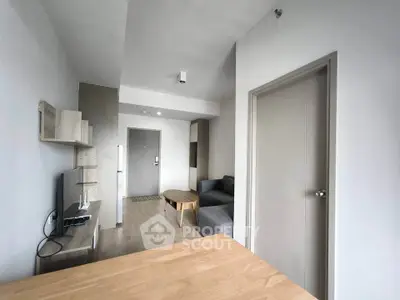 Modern living room with sleek furniture and neutral tones, featuring a cozy sofa and entertainment setup.