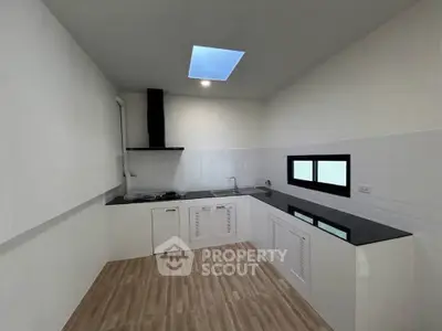 Modern kitchen with sleek countertops and skylight, featuring a gas stove and ample cabinetry.
