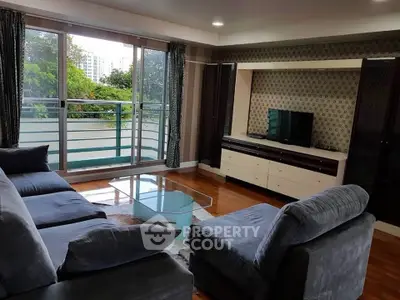 Spacious living room with modern furniture and large windows offering a serene garden view.
