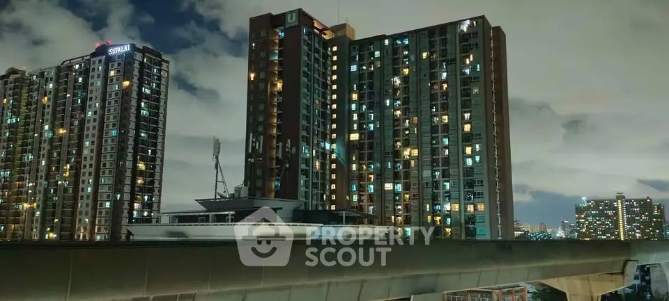 Stunning night view of modern high-rise residential buildings with city skyline in the background.