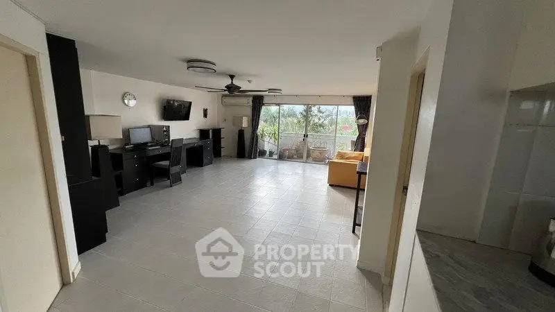 Spacious living room with modern decor and large windows offering natural light and garden view.