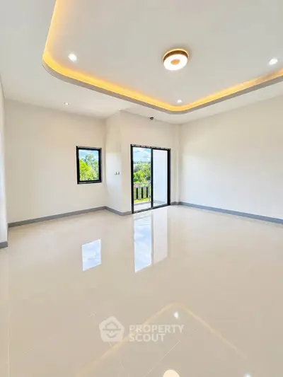 Spacious modern living room with elegant ceiling lights and large windows offering scenic views.