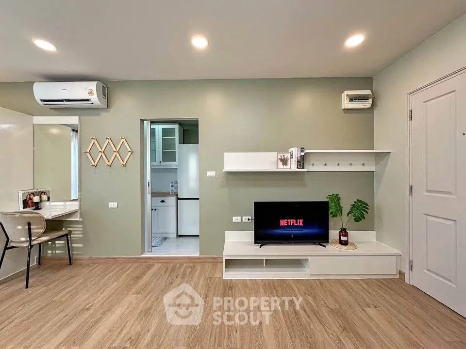 Modern living room with stylish decor and open kitchen layout, featuring wooden flooring and sleek furniture.