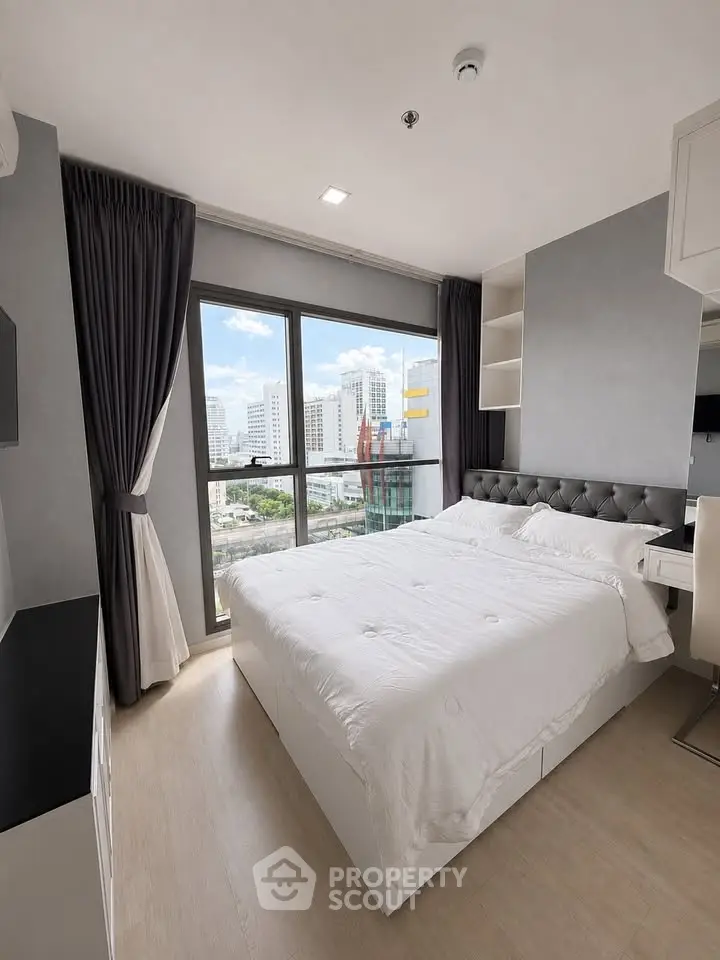 Modern bedroom with city view, featuring elegant decor and large windows for natural light.